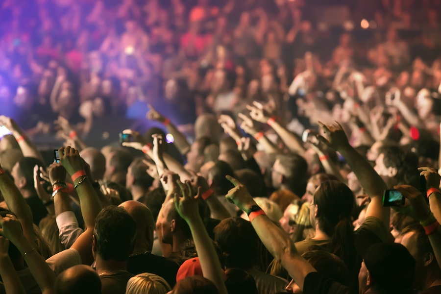 A large crowd at a concert. Most have their hands in their air or are filming with their phones.