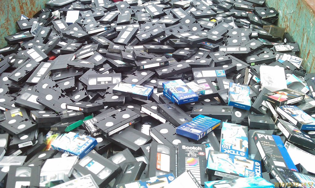 A huge pile of VHS tapes in a dumpster.