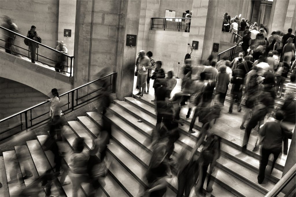 People walking up and down stairs in a large building.