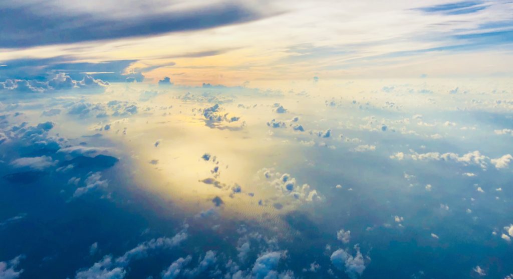 Seen from an airplane, clouds in the sky above and below.