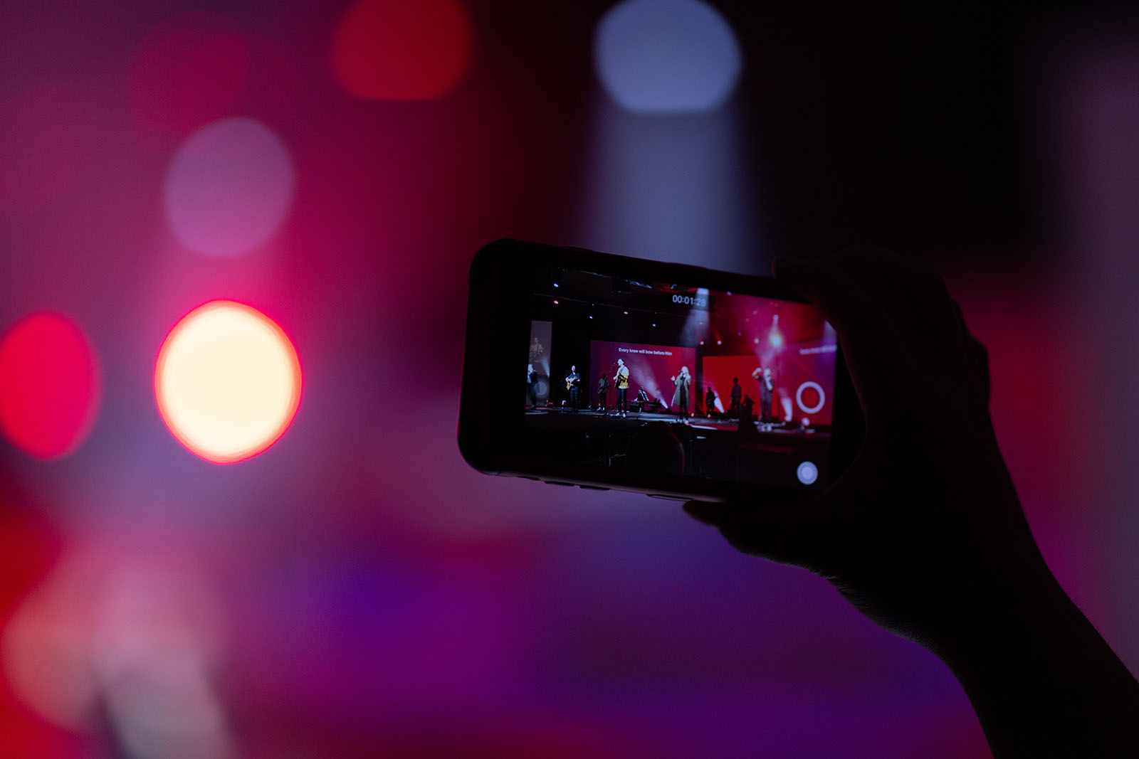 A person filming a concert with their smart phone.