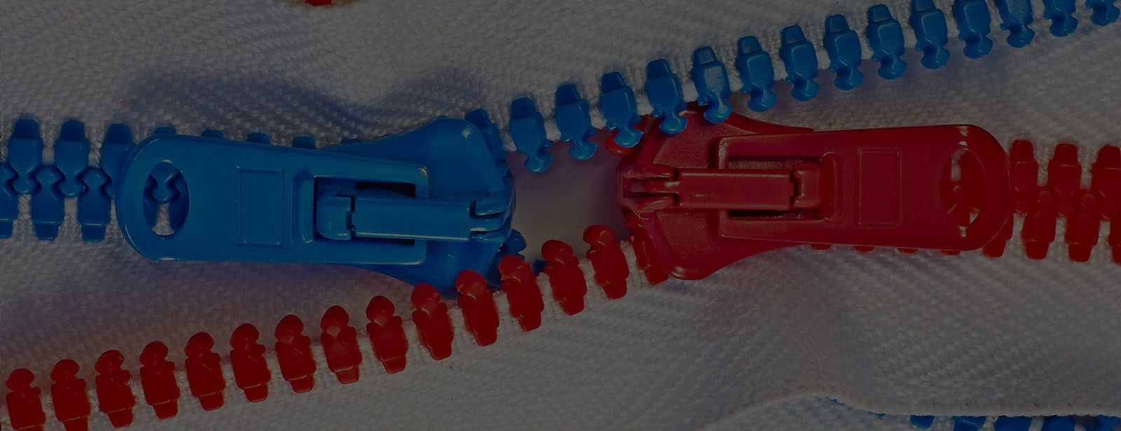 A red zipper and a blue zipper crossing each other.
