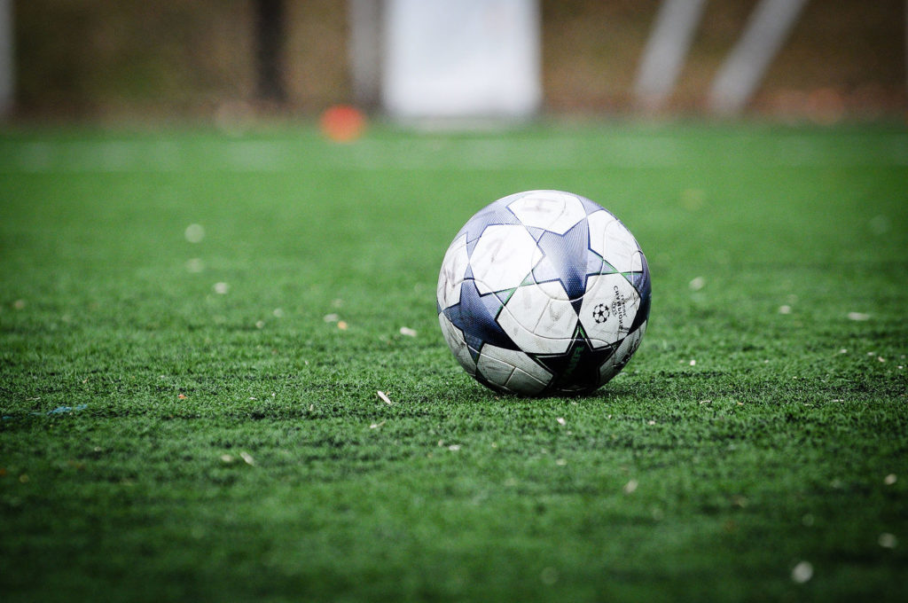 A blue and white soccer ball on a soccer field.