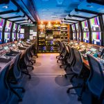 A long room full of monitors, chairs and various sound and editing equipment.