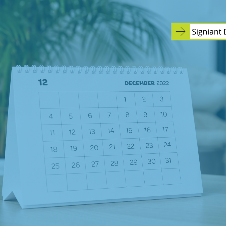 Signiant December Events with white calendar propped up on a table in the background